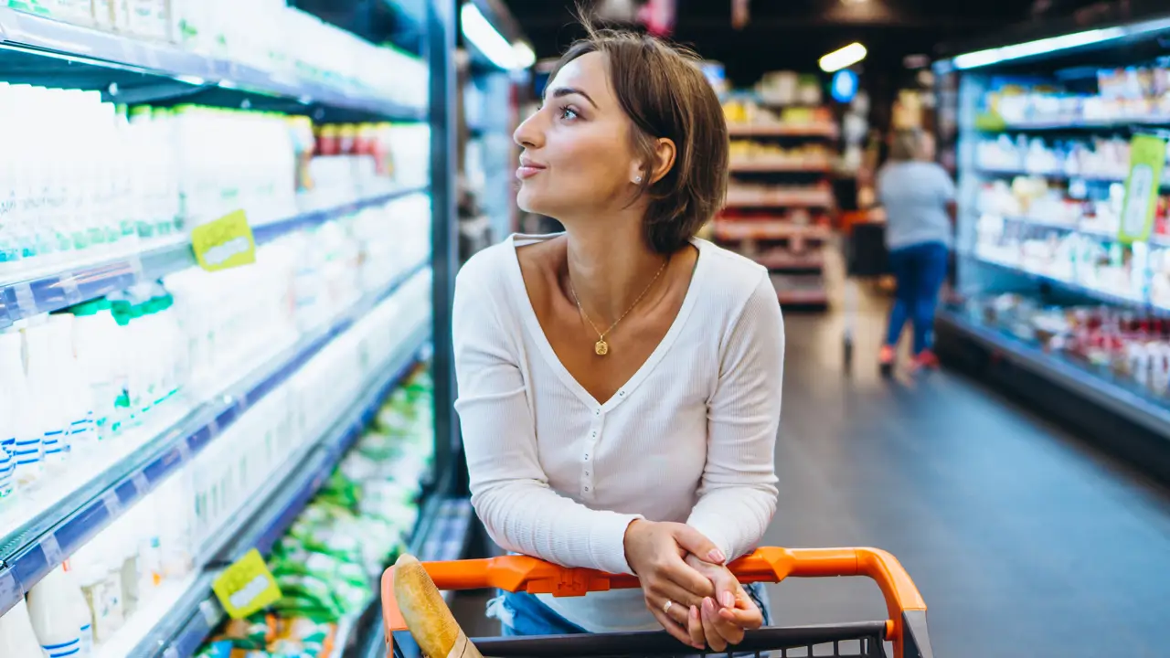 mujer de compras en la tienda de comestibles junto al refrigerador