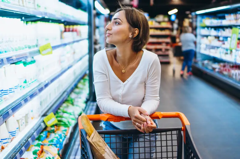 mujer de compras en la tienda de comestibles junto al refrigerador